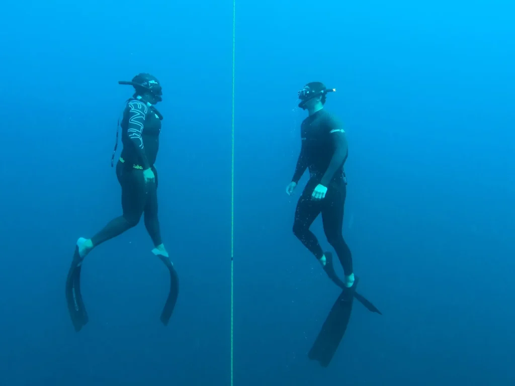 Two freedivers beside an underwater training line