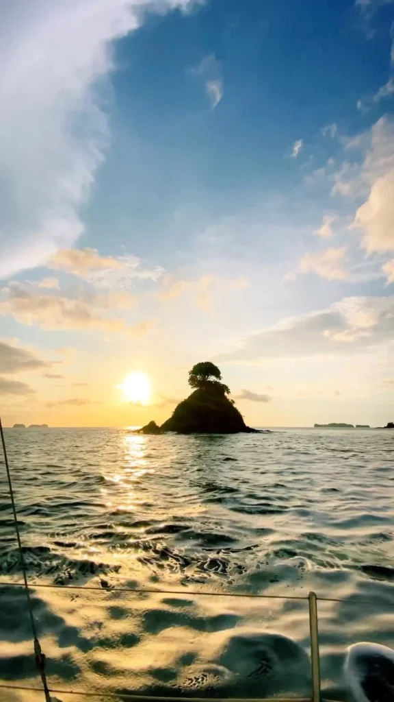 Golden sunset behind a tree-covered coastal islet viewed from the water
