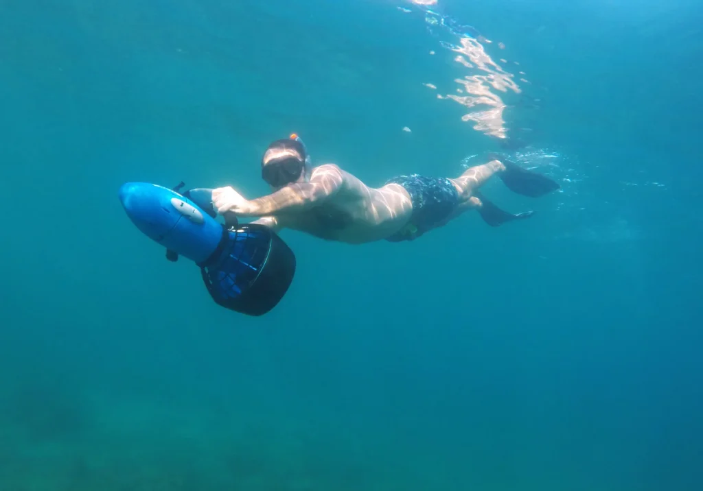 Snorkeler moving through blue water with a sea scooter
