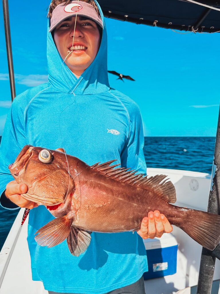 Angler holding a grouper aboard a Sea Breeze fishing boat in Tamarindo