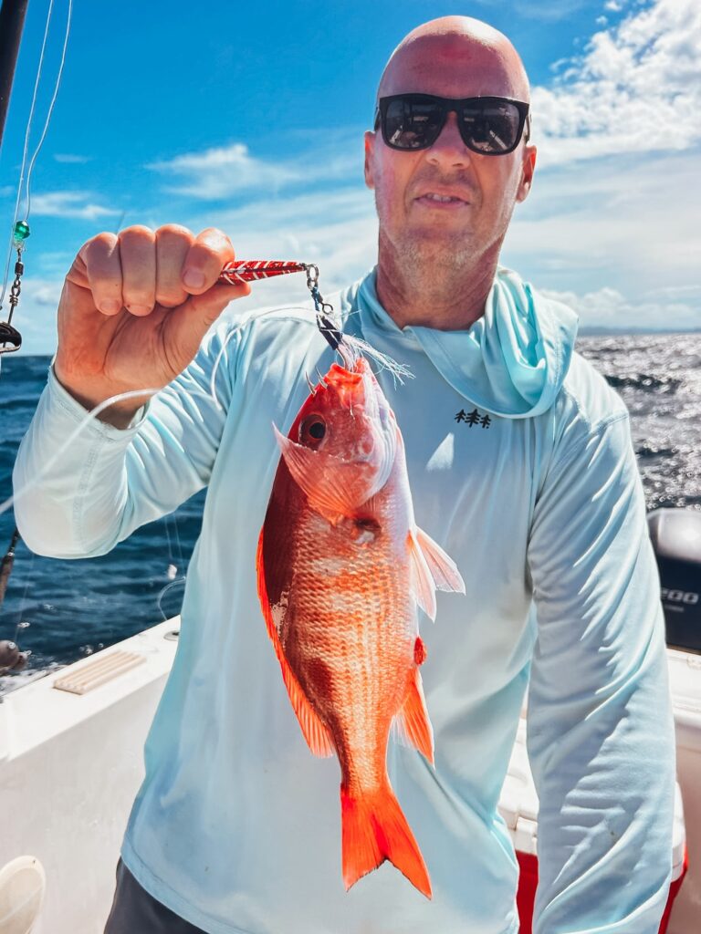 Angler holding a snapper aboard a Sea Breeze fishing boat in Tamarindo